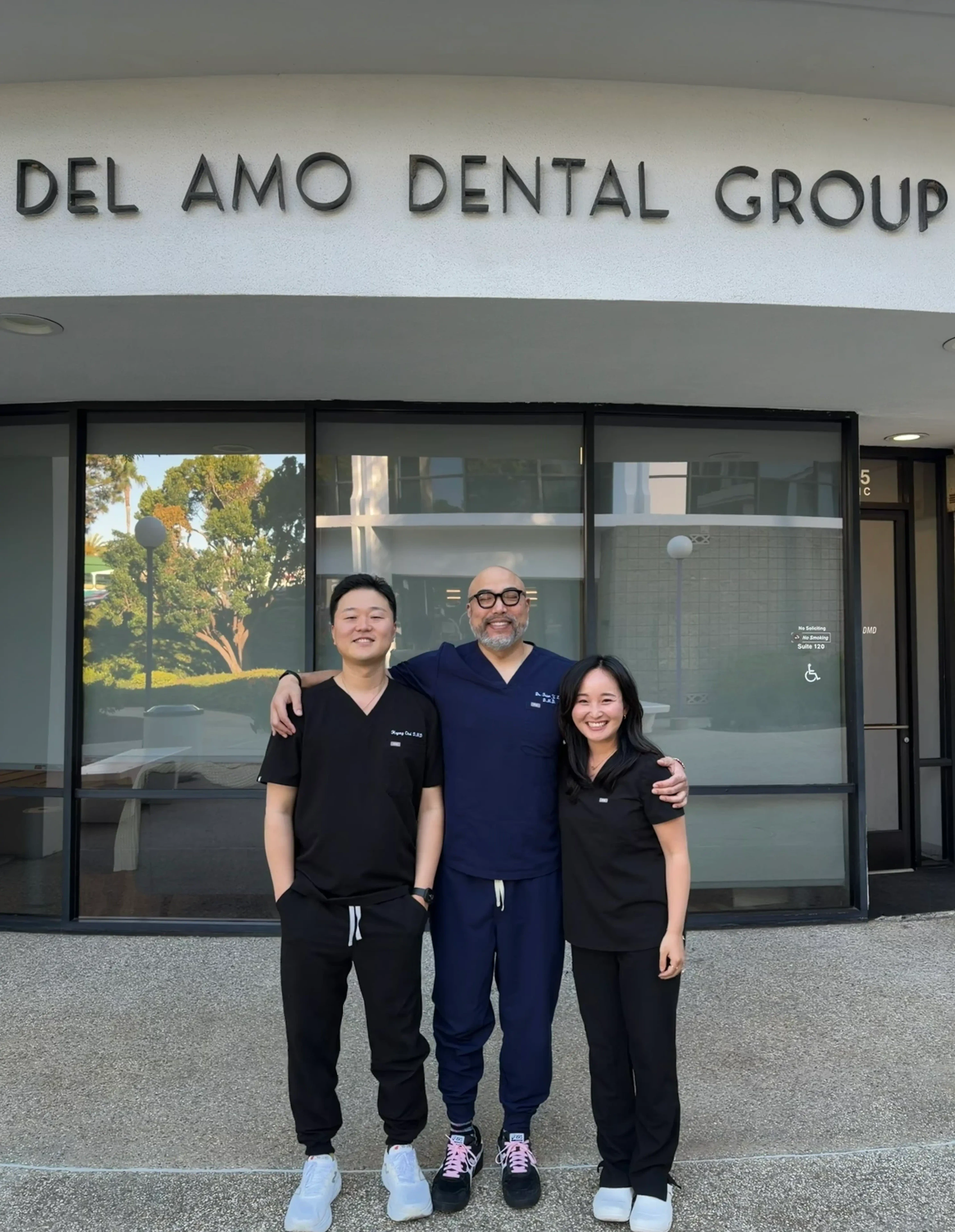 Dr. Hoyong Choi, Dr. Brian Y. Lee, and Dr. Ustina Huh standing together in front of Del Amo Dental Group